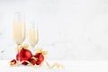 Bright New Year background with two fizz champagne wineglasses, shine christmas decoration - red balls, golden ribbon on soft.