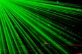 Bright nightclub green laser lights cutting through smoke machine smoke making light and rainbow patterns on the dance floor.
