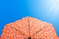 Bright orange beach umbrella against a clear blue sky lit by the rays of the sun Royalty Free Stock Photo