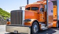 Bright orange big rig classic American bonnet semi truck tractor with painted accessories transporting cargo in stainless steel Royalty Free Stock Photo