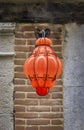 Bright orange blown Murano glass street light hanging outside in a street in Venice, Italy