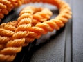 Bright orange braided nylon rope in tangled coil black background