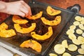 Bright orange butternut squash pieces grilled on electric grill, blurred woman hand moving pieces of vegetables over hot plate