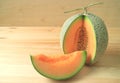 Bright orange color juicy ripe cantaloupe melon sliced from whole fruit isolated on wooden table Royalty Free Stock Photo