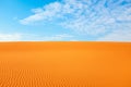 Bright orange color rippled desert sand and clear blue sky for a warm hot summer background