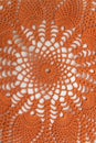 Bright orange crocheted product. Openwork napkin for decor on white background. Knitted lace pattern. Vertical frame