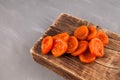 Bright orange dried apricots on an old wooden board. Gray background, top view, copy space Royalty Free Stock Photo