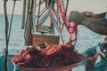 Bright orange fishing net with floats. Fisher boat in a sea. Hands of an old fisherman