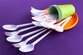 Bright orange and green set of disposable plastic tableware on purple background. Ecology problem. No plastic concept Royalty Free Stock Photo