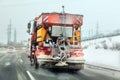 Bright orange gritter maintenance truck spreading deicing salt and sand on highway, view from car driving behind Royalty Free Stock Photo