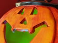 Bright orange Halloween pumpkin. Cut holes for mouth, nose and eyes. Green scary glow from the inside of the pumpkin. Close-up