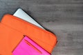 Bright orange laptop case with pink note book and pen flatlay Royalty Free Stock Photo