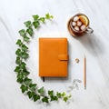 Bright Orange Leather Notebook with Ivy Vine, Pencil, and Iced Tea on Marble Surface Royalty Free Stock Photo