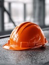 Bright orange protective helmet resting on a textured metal surface in an industrial setting with blurred background for safety Royalty Free Stock Photo
