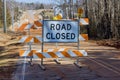 A bright orange road closed ahead sign caution cones barricades are blocking