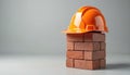 Bright orange safety hard hat rests on five red bricks. Construction, building process, worker safety on site. Protective helmet Royalty Free Stock Photo