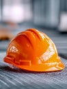 Bright orange safety helmet resting on metal surface in industrial setting with blurred background highlighting construction and Royalty Free Stock Photo