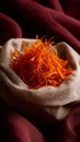 Bright orange saffron threads in a light cloth bowl on a dark red background Royalty Free Stock Photo