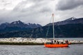 bright orange sailboat visiting the beagle channel, with rocky islands inhabited by cormorants. Ushuaia, Argentina