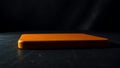 Bright orange square object on dark reflective surface. Royalty Free Stock Photo