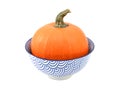 Bright orange sugar pumpkin in a blue and white bowl