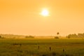 Bright orange sun at sunrise over a field Royalty Free Stock Photo