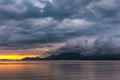 Bright orange sunrise on the coast with dark dramatic clouds billowing over mountains in the distance. Beaumaris Royalty Free Stock Photo