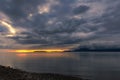 Bright orange sunrise on the coast with dark dramatic clouds billowing over mountains in the distance, North Wales Royalty Free Stock Photo