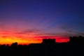 Bright orange sunset over the city in the evening. Bright lights of high-rise buildings of urban buildings. Silhouette of Royalty Free Stock Photo