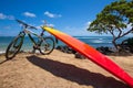 Bright orange surfboard and mountain bike on beach