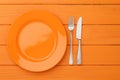 Bright orange table setting with plate and cutlery on wooden surface for dining inspiration Royalty Free Stock Photo