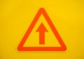 Bright orange warning triangle sign with an upward arrow symbol on a vibrant yellow background Royalty Free Stock Photo