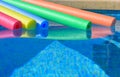 Five brightly coloured pool noodles in a swimming pool, no people