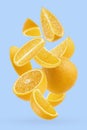 Bright oranges closeup levitation as flow, art composition. Whole, half and quarter pieces fruits on pastel blue background Royalty Free Stock Photo