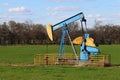 Bright painted old abandoned oil well derrick green meadow pasture Royalty Free Stock Photo