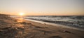 Bright panoramic horizontal warm orange sunset on the evening coast of the Black Sea with foamy waves of warm surf Royalty Free Stock Photo