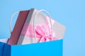 Bright paper shopping bag with gift box on light blue background, closeup Royalty Free Stock Photo