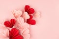 Bright and passion Valentines day background - curved flow of pink and red paper ribbed hearts flying on soft light pastel pink. Royalty Free Stock Photo