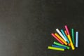 Bright pastel crayons lying on a black school board. Children`s