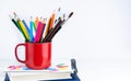 Bright pencils in a red mug on the books on the desk. Back to school. Banner. Place for text. Selective focus Royalty Free Stock Photo