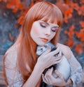 Bright photo, red-haired girl with straight hair and bangs holds cute sleeping ferret in her hands, lady with closed Royalty Free Stock Photo