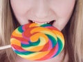 Bright picture of hungry blondie with color lollipop