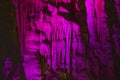 Bright pink abstract background of stalactites, stalagmites and stalagnates in a cave underground, horizontal