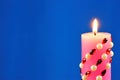 Bright pink candle, lit on a blue creative background. The candle illuminates, and a symbol of faith, hope, love, Christmas Royalty Free Stock Photo