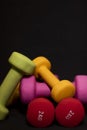 Bright pink, green, red and yellow small dumbbells on a black background. Sport concept. Royalty Free Stock Photo