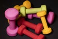 Bright pink, green, red and yellow small dumbbells on a black background. Sport concept. Royalty Free Stock Photo