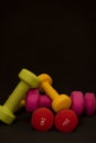 Bright pink, green, red and yellow small dumbbells on a black background. Sport concept. Royalty Free Stock Photo