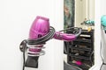 bright pink hair dryer with coiled cord on a wall bracket