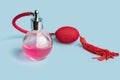 Bright pink perfume in a glass transparent bottle with red vintage style sprayer with an airbag and tassel on pastel baby pink