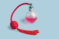 Bright pink perfume in a glass transparent bottle with red vintage style sprayer with an airbag and tassel on pastel baby pink